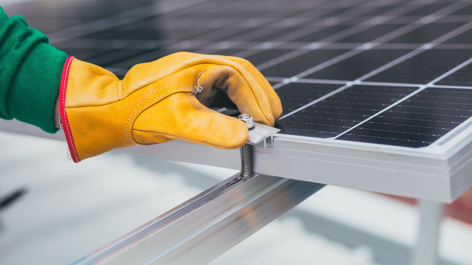Gloved hand fastening a solar panel